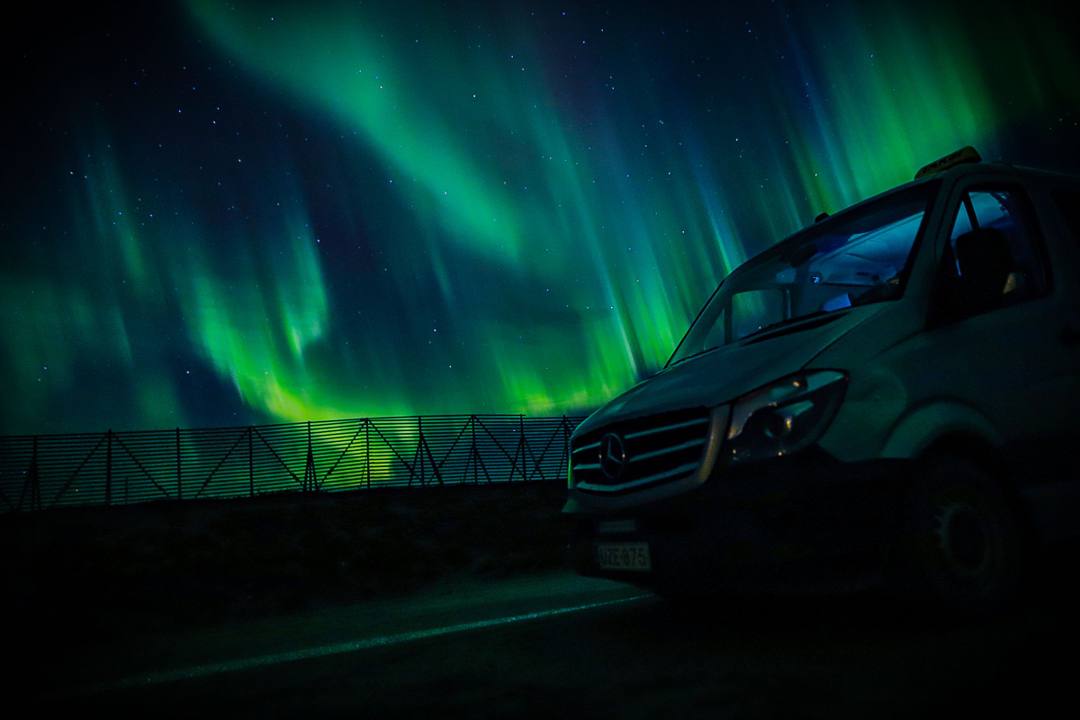 Black Mercedes-Benz van parked under green Northern Lights at night
